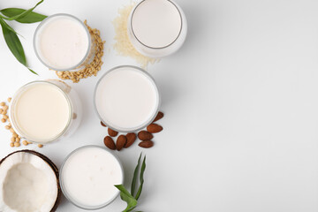 Different types of vegan milk and ingredients on white table, flat lay. Space for text