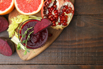 Fototapeta premium Tasty beetroot smoothie in glass, microgreens, fresh vegetables and fruits on wooden table, top view with space for text. Vegan drink