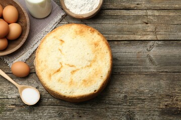 Tasty sponge cake and ingredients on wooden table, flat lay. Space for text