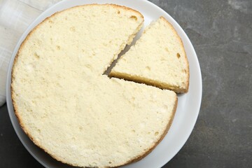 Delicious cut sponge cake on grey textured table, top view