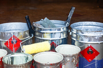 Empty paint buckets containing used rollers and brushes.