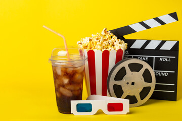 Tasty popcorn in buckets and cold cola drinks with cinema tickets, movie clapper and 3D eyeglasses...