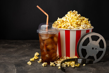Tasty popcorn in buckets and cold cola drinks with cinema tickets, movie clapper and 3D eyeglasses...