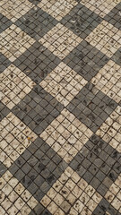 Old checkered stone pavement forming geometric pattern in Prague. Vertical mobile photo