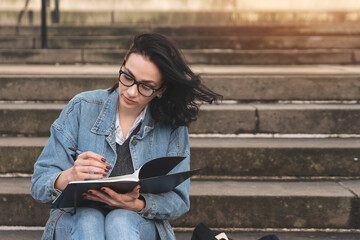 Young Woman Creatively Journaling on Steps in Peaceful Urban Setting During Golden Hour