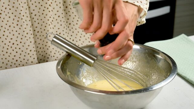 Woman cooking homemade mayonnaise sause adding pepper to metal bowl on kitchen, hands close-up. Cooking sauce for salad, meat dishes. Dressing for different dishes. Culinary, cuisine concept.