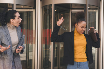 Two Women in Heated Conversation Outside Modern Building During Daylight Hours