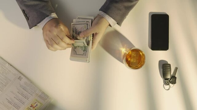 Top view of man counting large wad of us dollars money banknotes, flipping through bills, taking or borrowing money in credit.