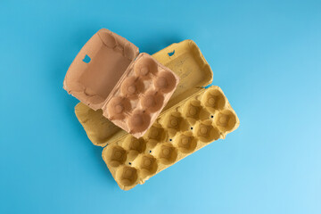 empty egg cartons stacked on a blue background, Ideal for recycling, storage solutions, packaging design discussions, recycling paper craft concept
