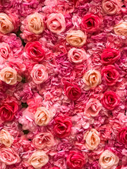 Profusion of artificial roses, arranged on a wall in an urban corridor, for shoppers and tourists to use freely as a background for Valentine photos and selfies on the spur of the moment