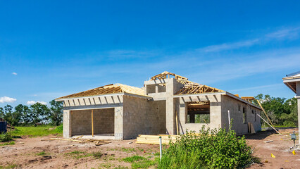 Concrete shell of a single-family house under construction, with roof in progress, in a suburban...