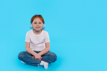 Young Girl Enjoys Music in Serene Blue Setting While Sitting Cross-Legged on  Floor