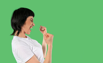 Joyful Woman Celebrating Success With Enthusiastic Gestures Against Vibrant Green Background