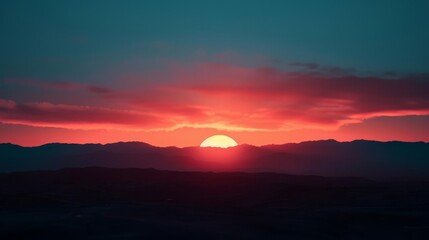 Obraz premium Vibrant red sunset over a mountain range.