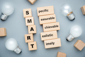 SMART acronym on wood blocks with glowing light bulbs, smart goal setting concept