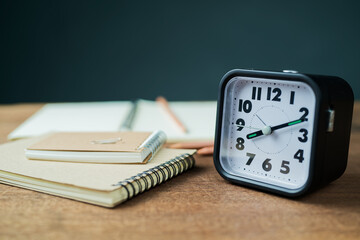 Closeup a clock on the table with some notebooks, create writing and time concept
