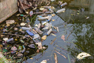 Much garbage floating and stucking on the water of a canal in the city