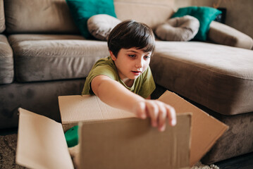 Happy cheerful kid boy packing his toys for delivery donation box. Charity and recycling