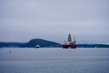 Offshore oil rig and ship with mountainous backdrop