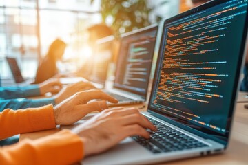 Hands typing on laptops with programming code on screens, showcasing modern technology and teamwork in a bright office environment.