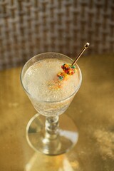 Sparkling drink with candy on golden cocktail pick