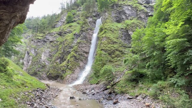 Static view of a scenic waterfall on high mountain covered by greens in Liechtensteinklamm, Austria