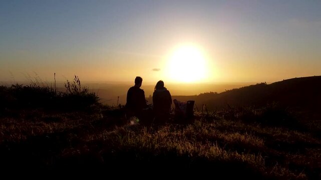 Drone flight captures silhouettes of a couple romantically watching the sunset