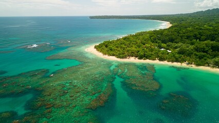 Aerial view of tropical coastline with beach and coral reefs.