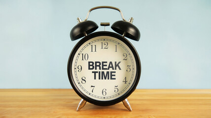 An alarm clock with the text "BREAK TIME" in the middle of it on a wooden surface and blue background.