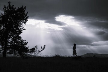 Silhouette of a woman with sun rays breaking through clouds