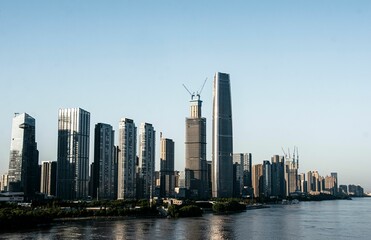 Fototapeta premium Of modern skyscrapers along a river in a city during daytime.