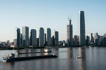 Obraz premium Modern cityscape with skyscrapers and river cargo ships.
