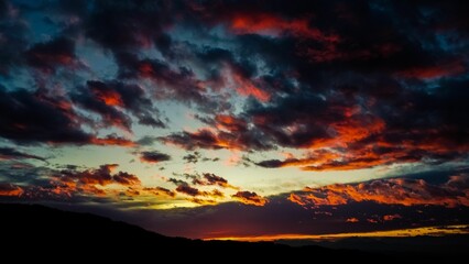Stunning sunset with vibrant red and orange clouds over a silhouetted mountain range