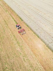 Aerial view of a red tractor plowing the field on a sunny summer day