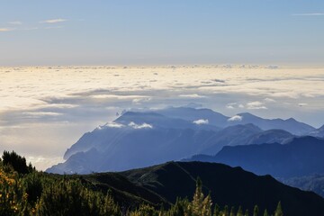 Breathtaking mountain range covered in clouds with clear blue sky, Madeira Island, Portugal