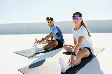 A couple practices the warrior pose on yoga mats, exhibiting strength and focus under a clear sky.