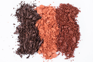 Scattered eye shadows in different shades. Cosmetics texture, white background.