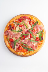 Pizza with prosciutto, ham, arugula, spinach, tomatoes, pesto, cheese and parmesan. Italian cuisine. 