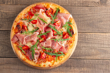 Pizza with prosciutto, ham, arugula, spinach, tomatoes, pesto, cheese and parmesan. Italian cuisine. 