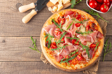 Pizza with prosciutto, ham, arugula, spinach, tomatoes, pesto, cheese and parmesan. Italian cuisine. 