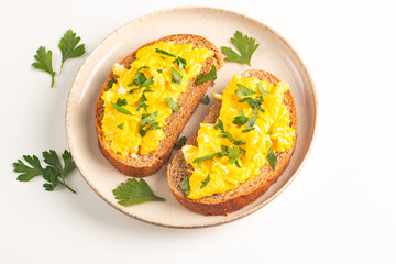 Scrambled eggs with green herbs on wheat-rye crispy toast.