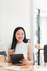 A smiling woman using tablet in modern workspace, exuding confidence and focus