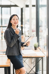 Professional woman smiling in modern office, holding tablet and pen