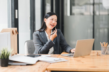 A professional woman is engaged in phone call while working on her laptop