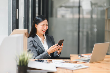 A professional woman smiles while using her smartphone in modern office