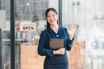 Smiling woman in blue dress welcoming customers at open cafe