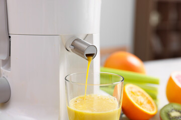 Modern juicer, glass and fresh fruits on table in kitchen, closeup