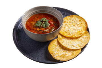 Nacho chips in black bowl with Mexican soup isolated on white background. Homemade taco chicken soup in a rustic pot with tortilla chips