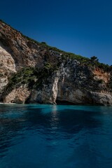 Fototapeta premium Vertical scenic view of a blue sea waters with rocky shoreline on a sunny day with blue sky