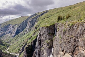 Scenic view of a waterfall cascading down a cliffside surrounded by lush greenery. Norway